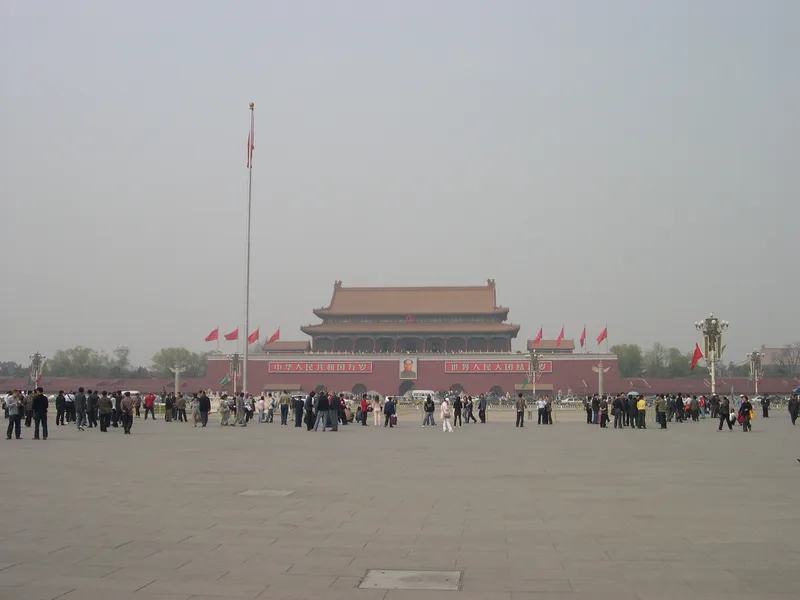 Tiananmen Square in haze, the Gate of Heavenly Peace in the distance behind a row of red flags