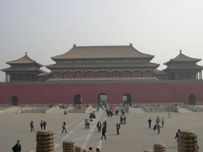 The Meridian Gate of the Forbidden City seen across a wide stone courtyard with scattered visitors