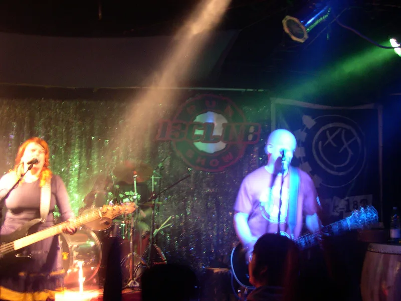 Katy and Kjell lit in purple and orange stage light, playing guitar and bass at 13 Club