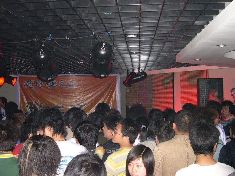 A dense crowd of young people filling the room at Bifengtang in Xinxiang, seen from the stage side
