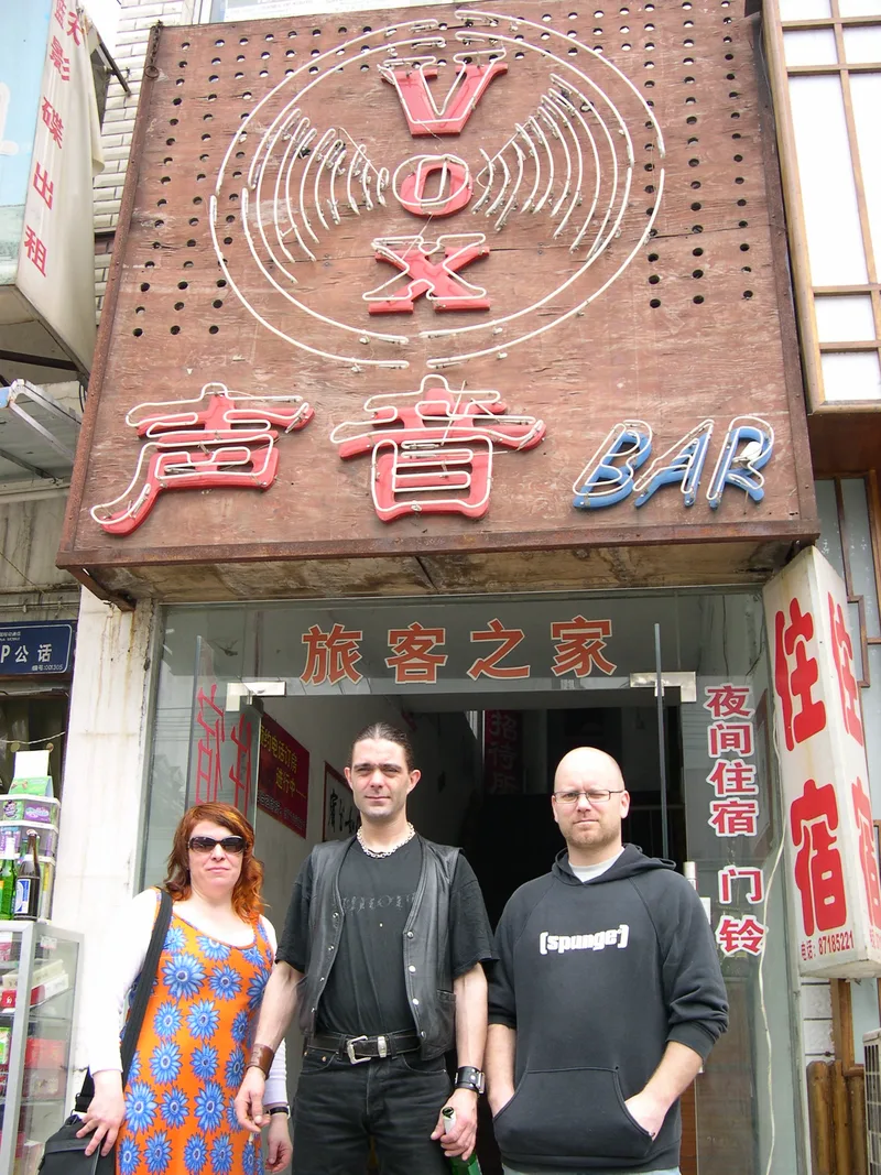 Kjell, Pez and Katy standing in the doorway under the VOX BAR sign in Wuhan