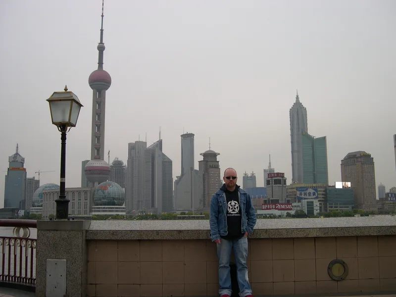 Kjell in sunglasses on the Bund promenade with the Oriental Pearl Tower and the Pudong skyline behind him