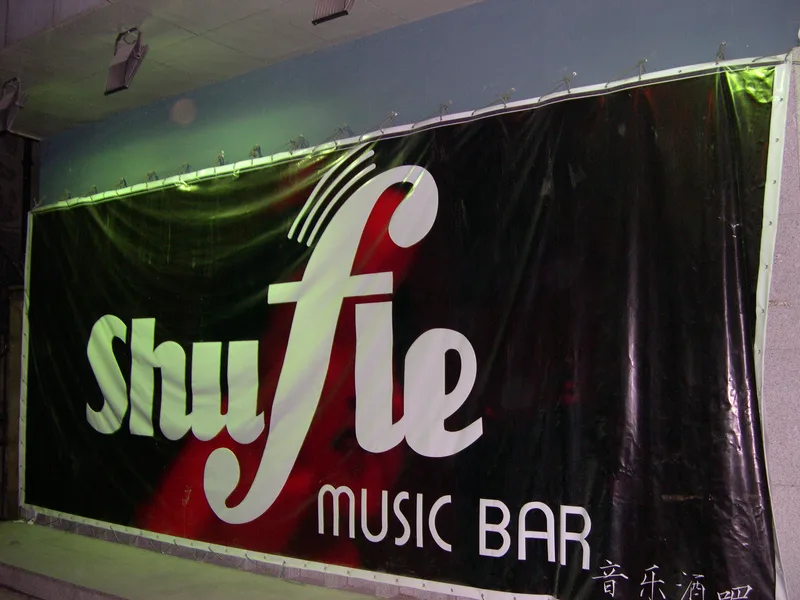 A large black and red Shufle Music Bar banner on the wall of the club